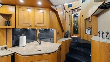 A compact kitchen with wooden cabinetry, a granite countertop, and a stainless steel sink.
