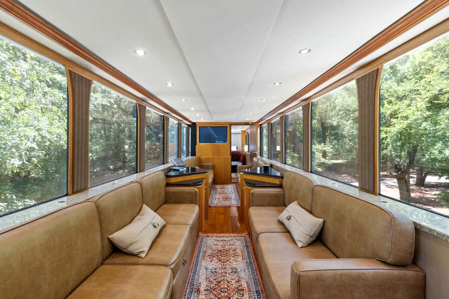 L'intérieur d'un wagon de train, avec des sièges en cuir, de grandes fenêtres et une table centrale.