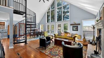 A spacious loft with a high ceiling, a spiral staircase, a large dining area, and a cozy seating area with a fireplace.