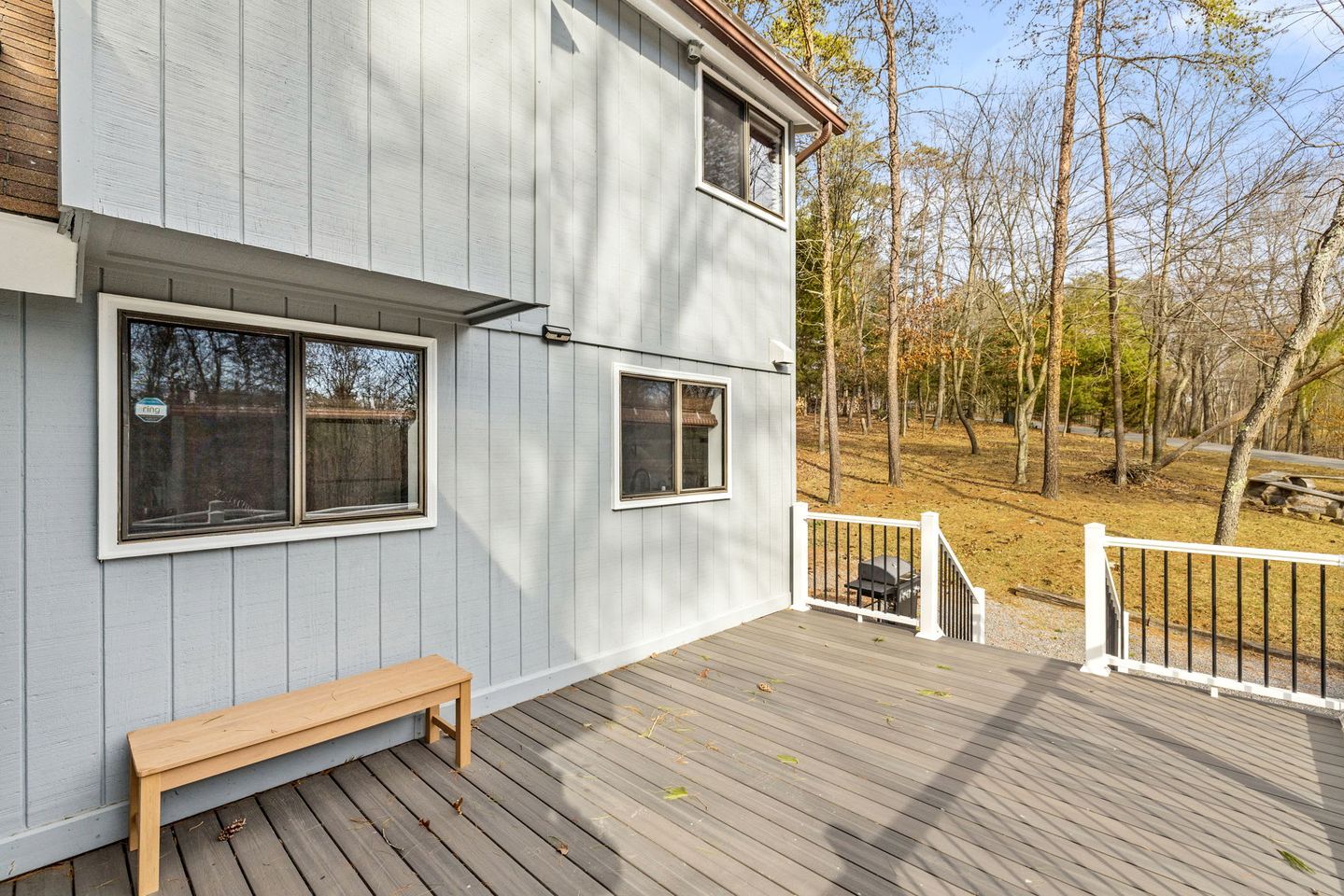 A two-story building with a deck, a bench, and a gated area.