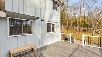 A two-story building with a deck, a bench, and a gated area.