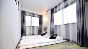 A room with two beds, a wall-mounted air conditioner, and a window with sheer curtains. - Spacious 4-bedroom apartment in heart of Osaka with AC (Osaka)