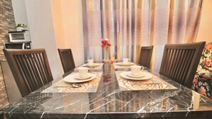 A dining table with four chairs, a vase with flowers, and a microwave on the wall. - Spacious 4-bedroom apartment in heart of Osaka with AC (Osaka)
