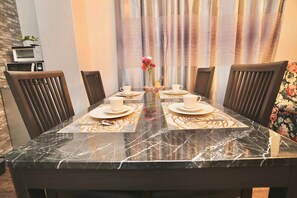 A dining table with four chairs, a vase with flowers, and a microwave on the wall. - Spacious 4-bedroom apartment in heart of Osaka with AC (Osaka)