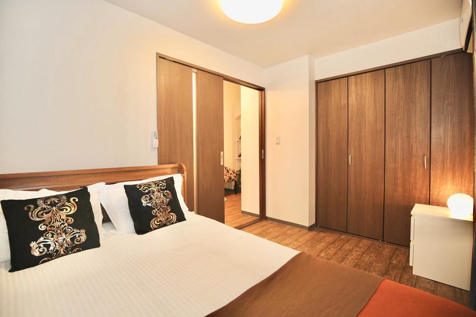 Quarto de hotel com cama, guarda-roupa e escrivaninha.