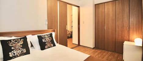 A hotel room with a bed, a wardrobe, and a desk.