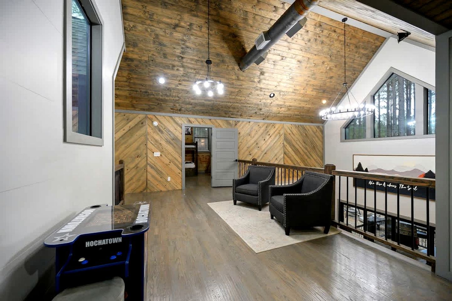 A spacious loft with a high ceiling, wooden beams, a piano, and a view of the outdoors.