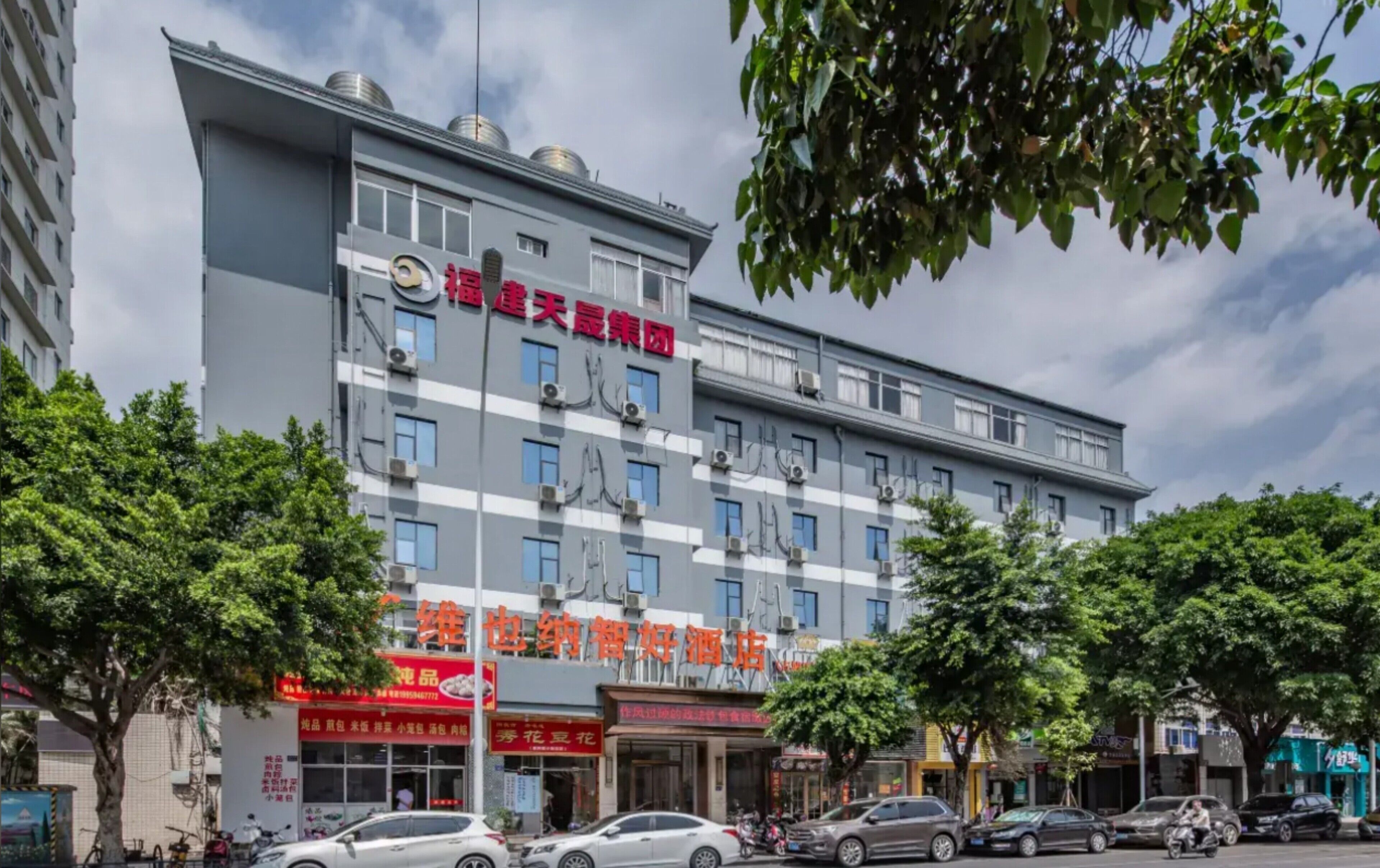 A multi-story building with a prominent red sign indicating a hotel.