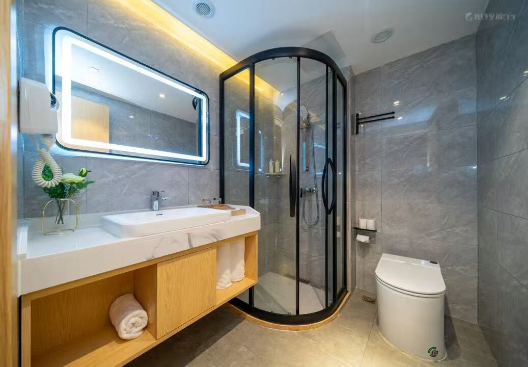 Un baño moderno con ducha de vidrio, tocador con espejo y un inodoro.