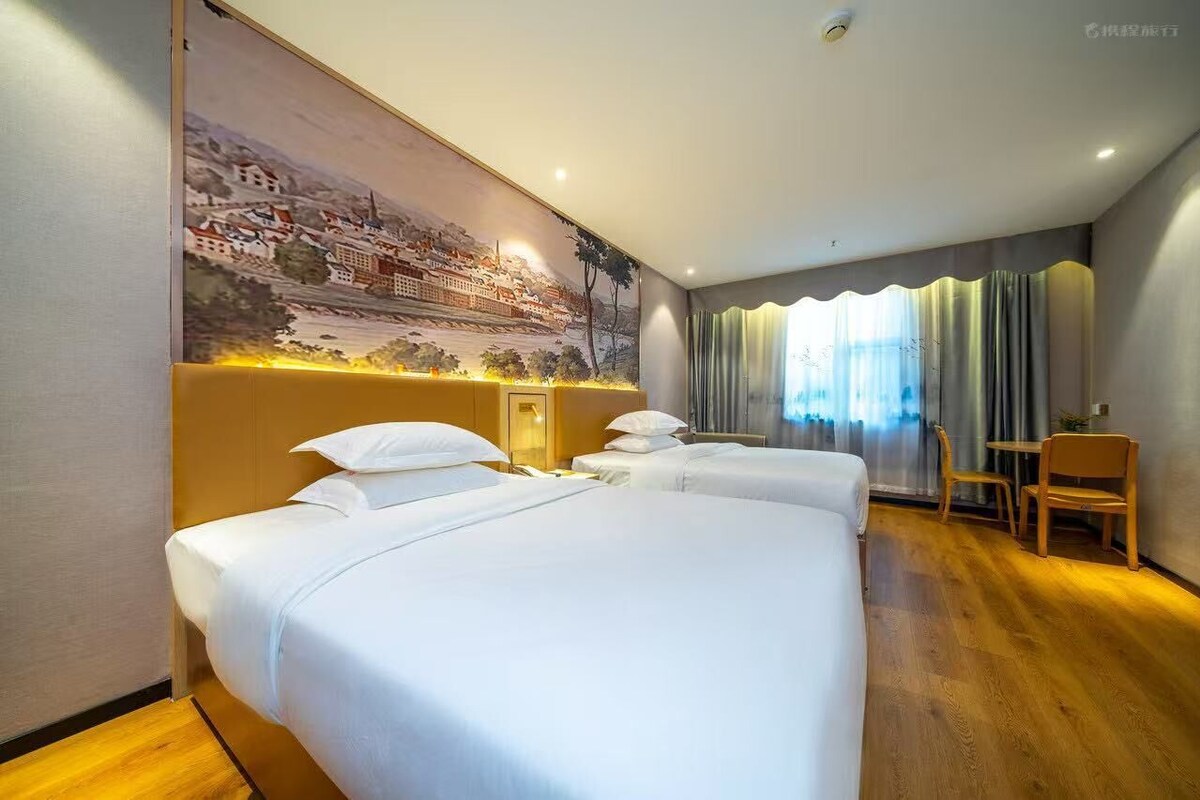 A hotel room with two beds, a desk, and a chair.