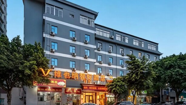 Een meerlaags hotel met een modern ontwerp, met een opvallende ingang en borden voor een restaurant.