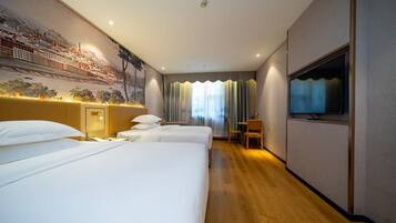 A hotel room with two beds, a TV, a desk, and a mural on the wall.