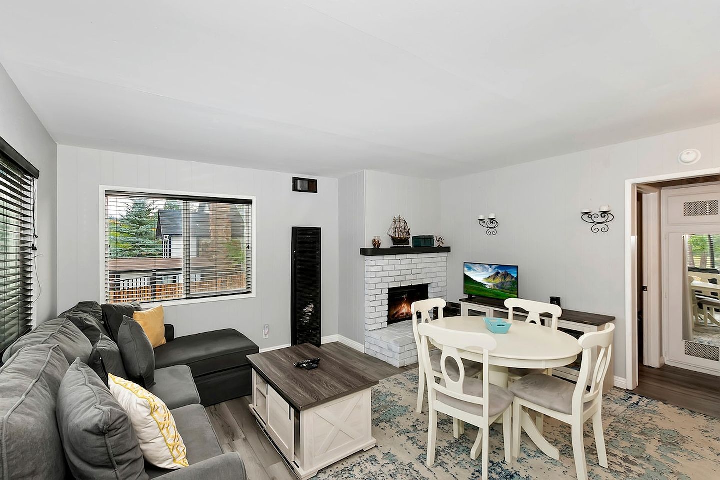 A living room with a sofa, coffee table, fireplace, TV, and dining area.