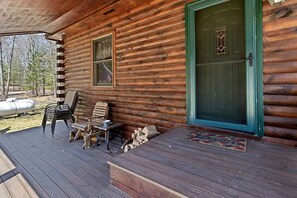 Eine Blockhütte mit Veranda, einer grünen Tür und Außenmöbeln.