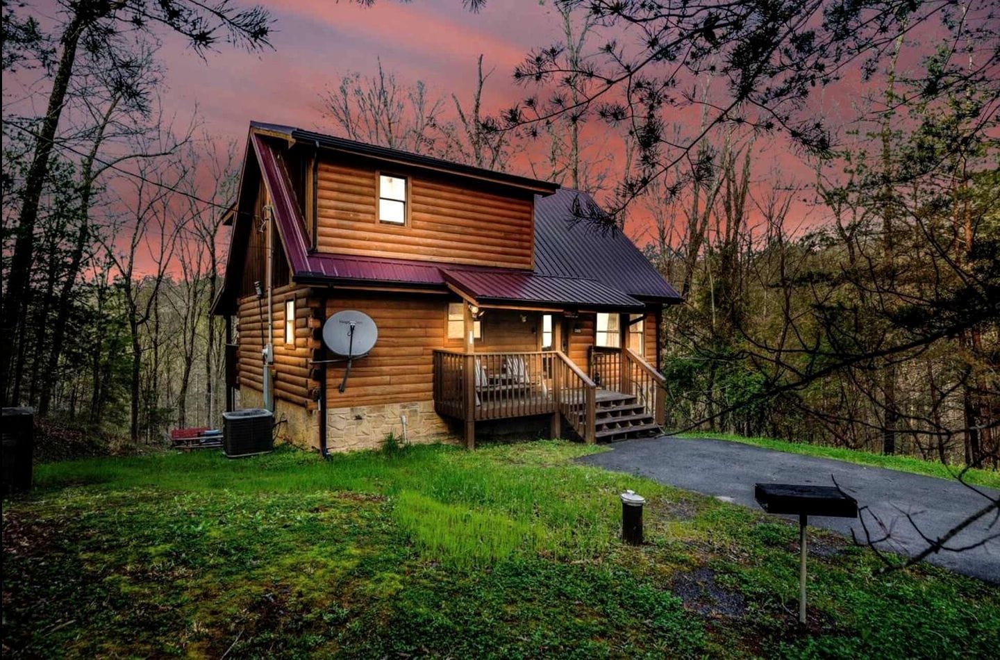 A log cabin with a porch, a satellite dish, and a driveway.