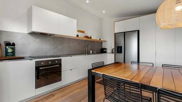 A modern kitchen with white cabinets, a wooden dining table, and black chairs.