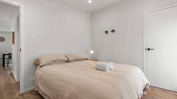 A bedroom with a bed, a nightstand, a wall clock, and a door.