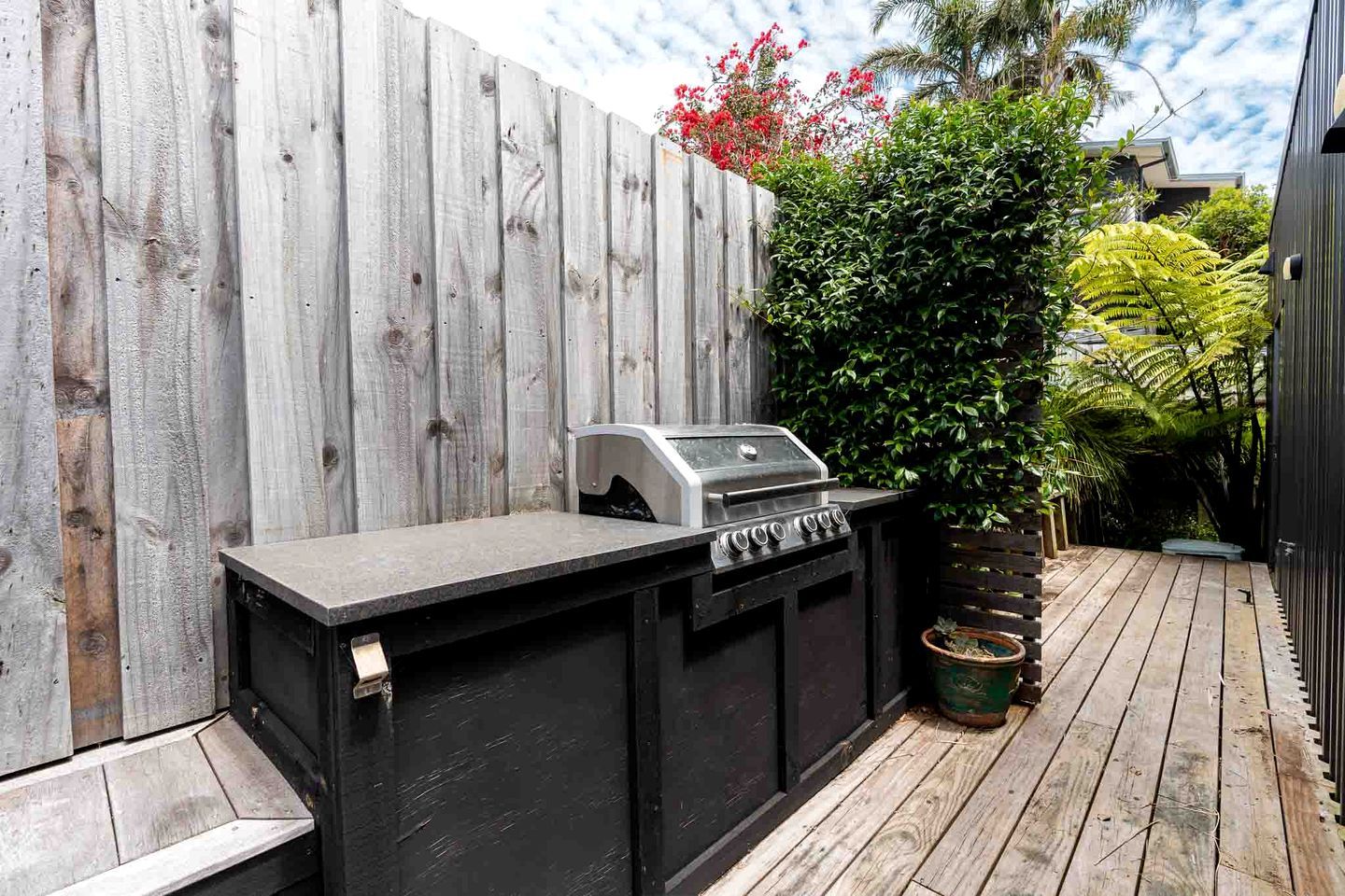 A wooden deck with a built-in grill and a wooden fence.