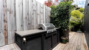 A wooden deck with a built-in grill and a wooden fence.