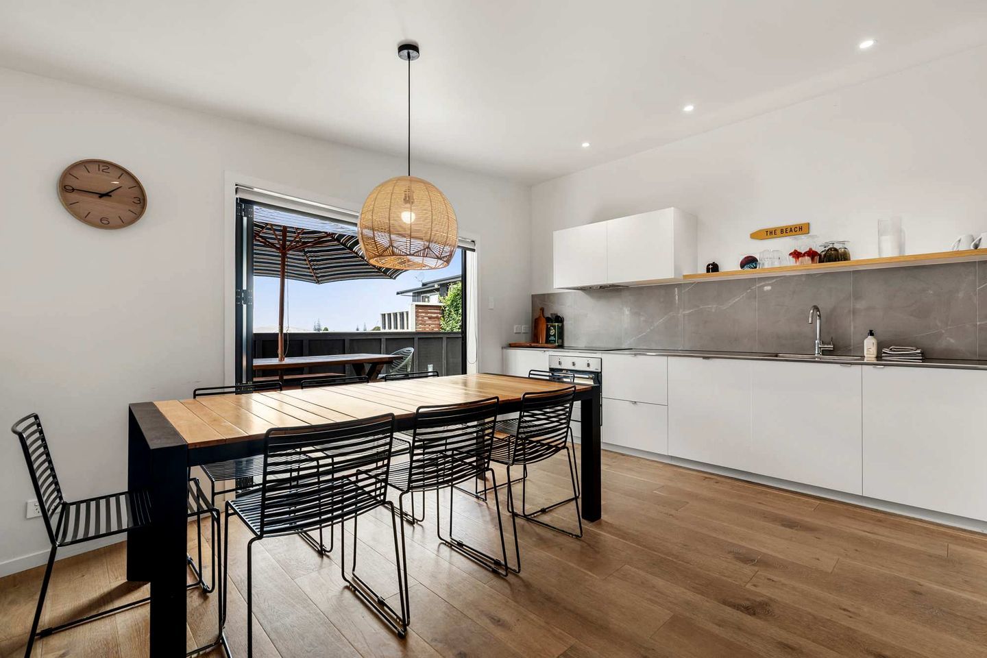 Une cuisine moderne avec un coin repas, une grande fenêtre et un luminaire suspendu.