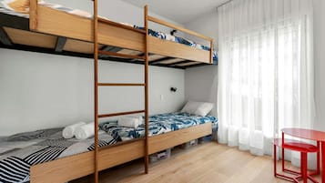 Una camera con un letto a castello, una scala, una scrivania e una finestra con tende.