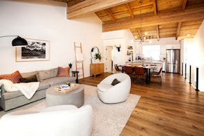 A modern living room with a sofa, coffee table, and armchair, a dining area with chairs and a table, and a kitchen with appliances. - Stylish Mountain-View Townhome with Modern Comforts near Lake Tahoe in Incline Village, Nevada (Incline Village)