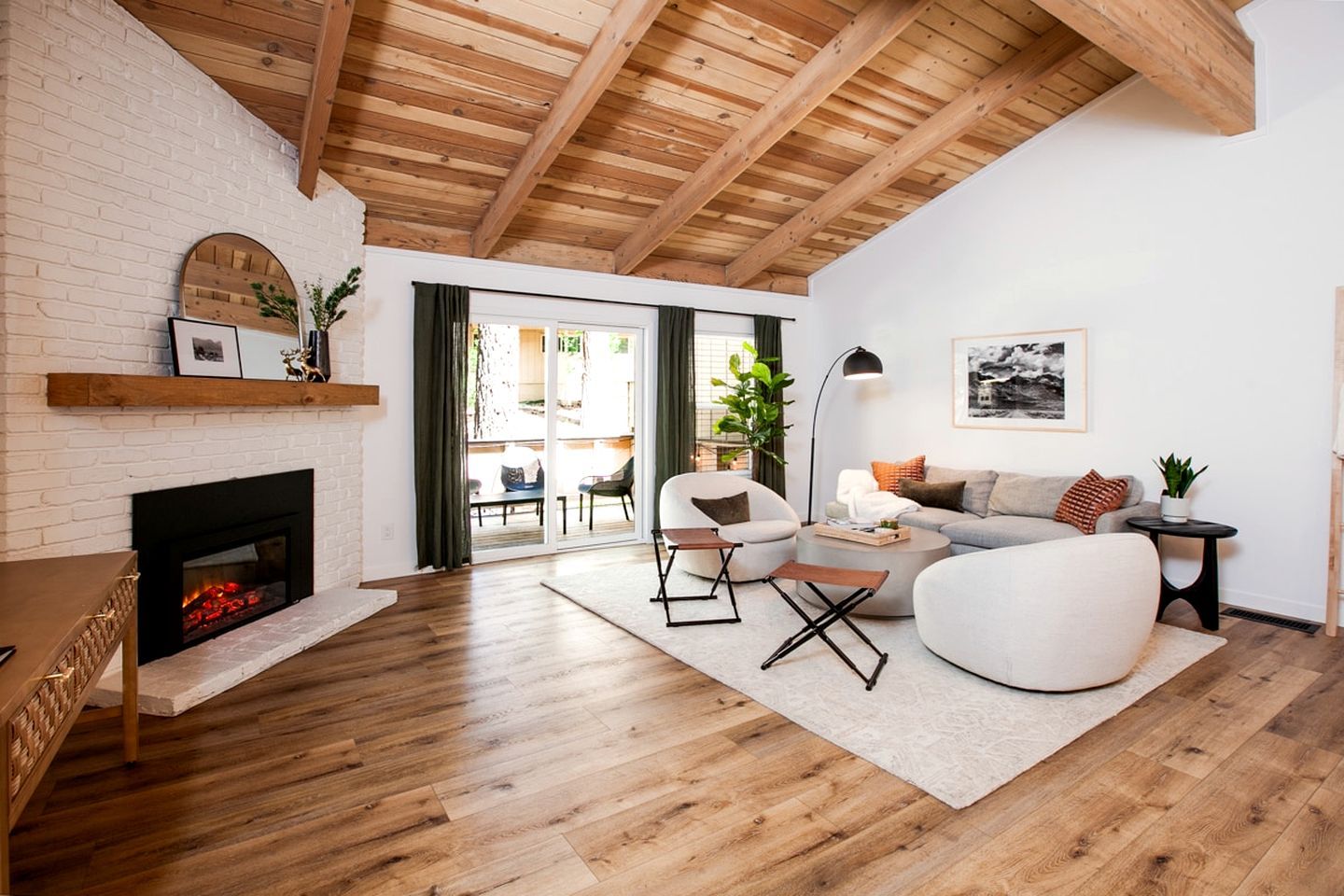 Een moderne woonkamer met een open haard, houten vloeren en een eethoek met een tafel en stoelen.