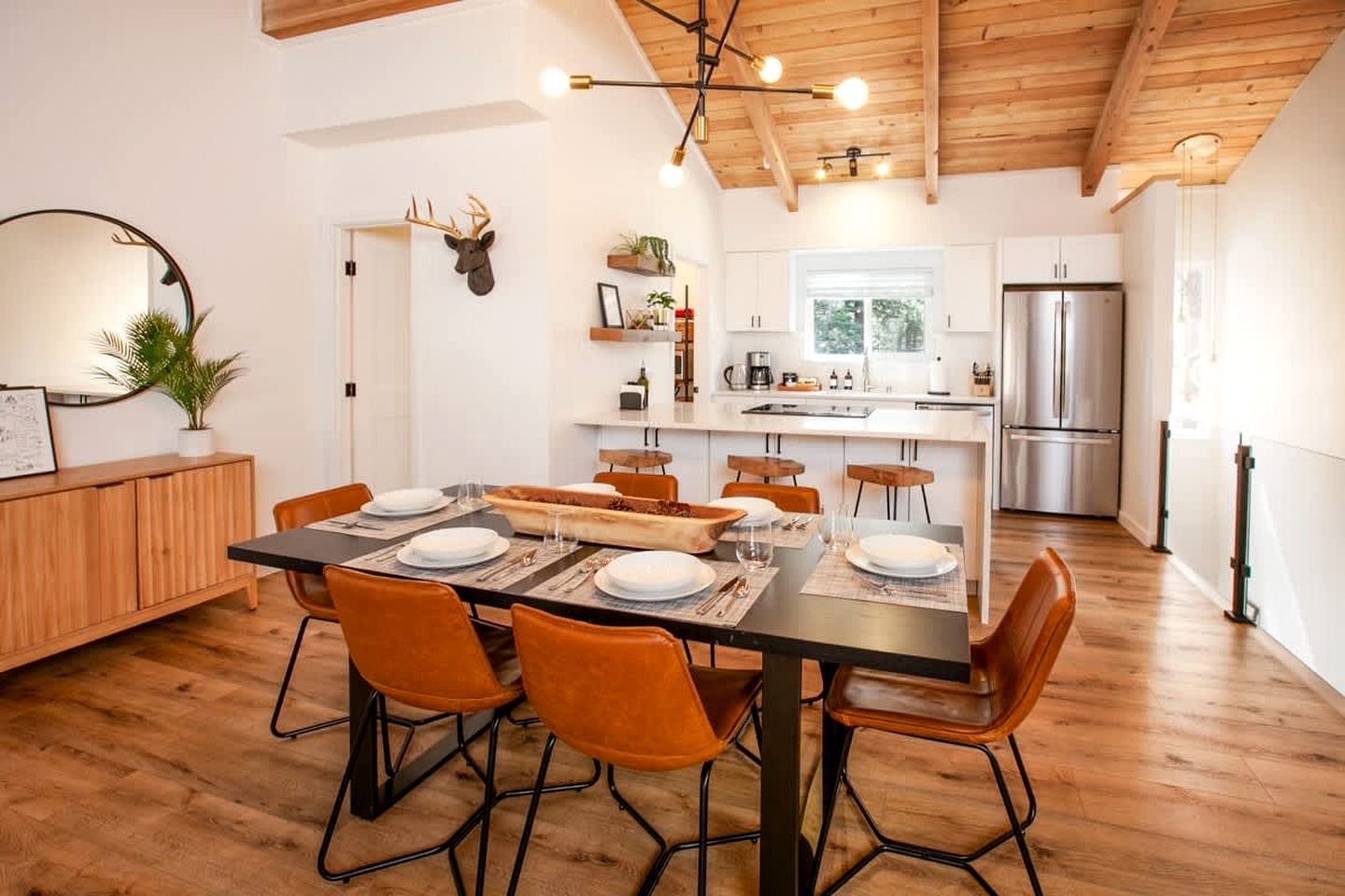 A modern kitchen with a central island, wooden cabinets, and a stainless steel refrigerator.