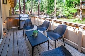 Eine Terrasse im Freien mit Grill, Stühlen und Tisch.