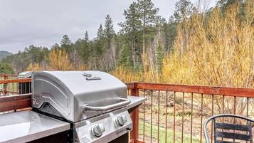 Ein Grill auf einer Terrassenanlage mit Blick auf einen Wald.