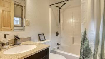 Une salle de bain avec un lavabo, des toilettes, une douche et un tableau encadré au mur.