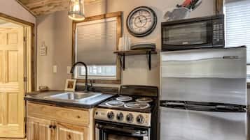 A kitchen with a stove, oven, sink, and a microwave.