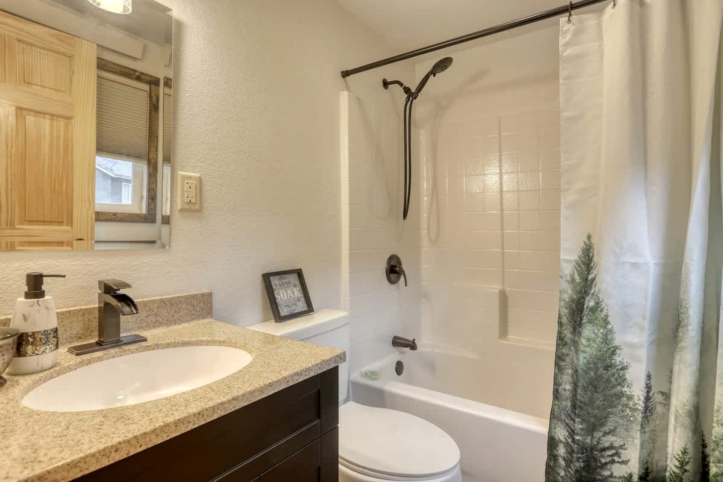 Une salle de bain avec un lavabo, des toilettes, une douche et un tableau encadré au mur.