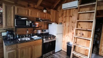 Eine Küche mit Holzwänden, ausgestattet mit einem Herd, einer Mikrowelle, einer Spüle und einem Kühlschrank.
