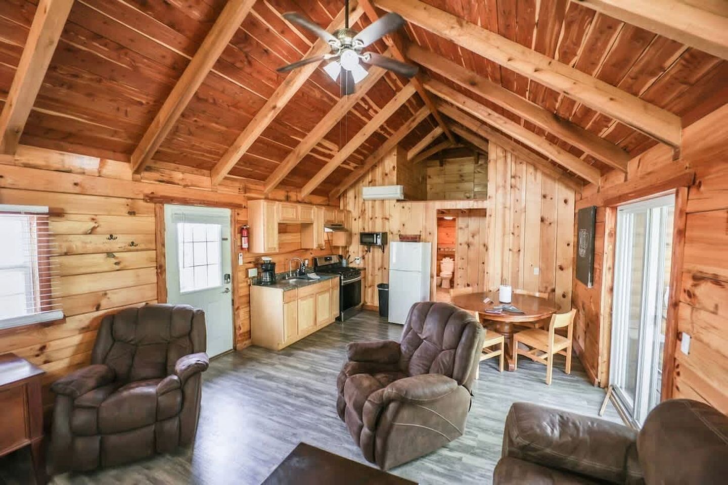A log cabin interior with a dining area, kitchen, and two leather recliners.