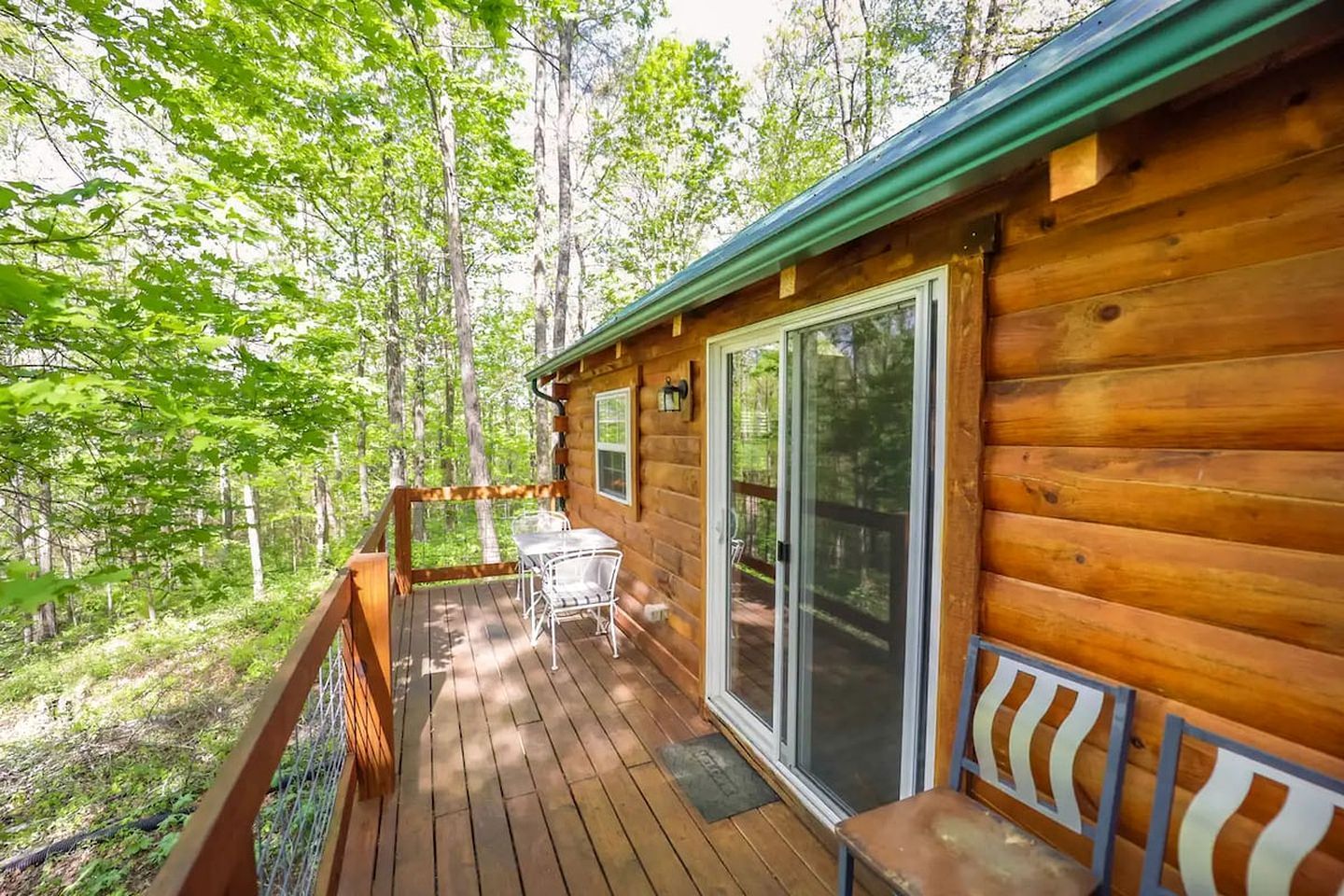 Une cabane en bois avec une terrasse, une table et des chaises.