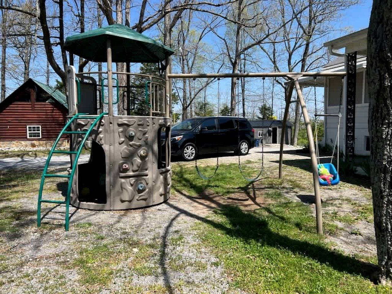 Un parque infantil con una estructura para escalar, columpios y un asiento para columpiarse.
