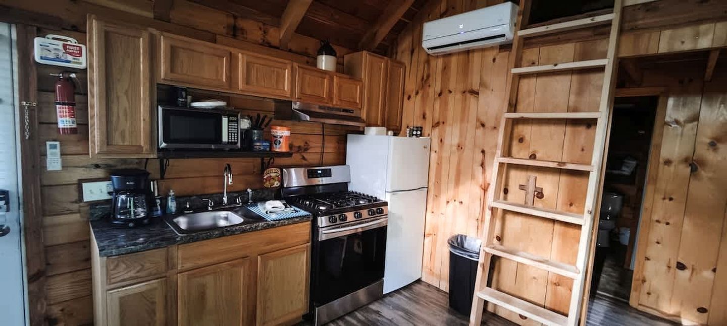 A wooden-paneled kitchen with a stove, microwave, sink, and refrigerator.