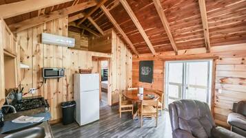 Een houten chalet van binnen, met een keukenhoek, eettafel en zitplaatsen.