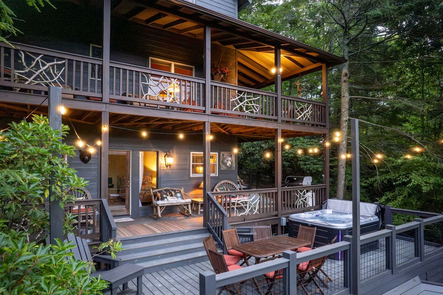 A multi-level deck with outdoor seating, a hot tub, and string lights.