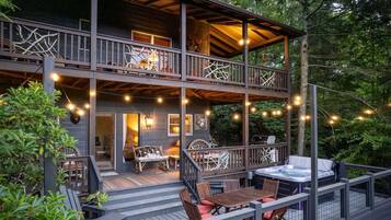 A multi-level deck with outdoor seating, a hot tub, and string lights.