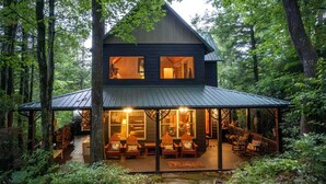 A two-story cabin with a covered porch, surrounded by forest. - Scenic Mountain Cabin with Hot Tub, Game Room & Firepit near Silver Run Falls – Cashiers, NC (Cashiers)