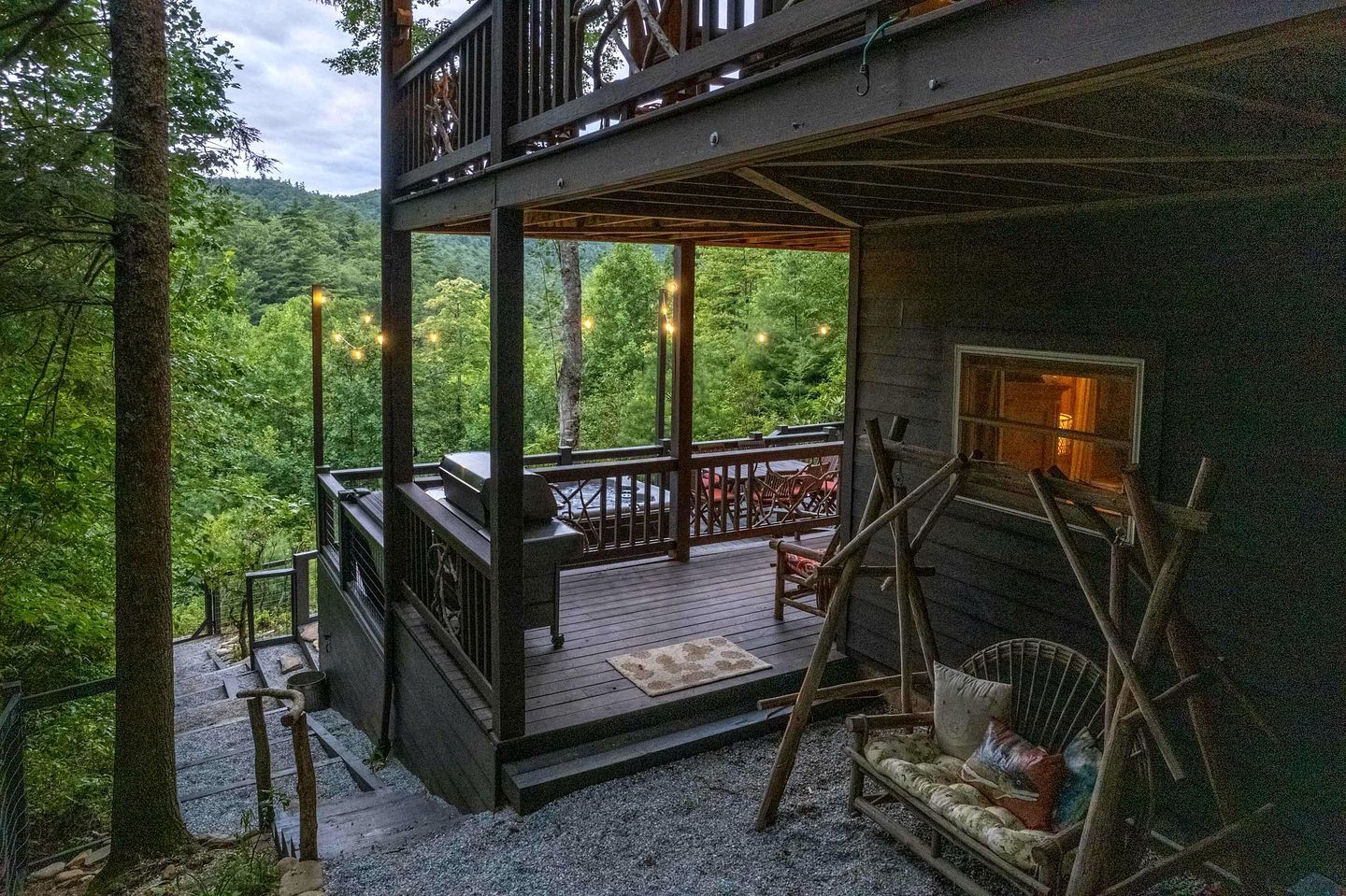 Une cabane en bois à deux étages, dotée d’une terrasse, de meubles d’extérieur et d’une cheminée.