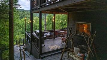 Une cabane en bois à deux étages, dotée d’une terrasse, de meubles d’extérieur et d’une cheminée.