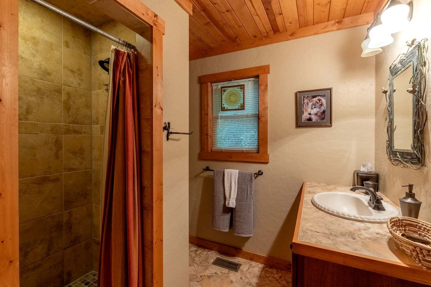Ein Badezimmer mit Dusche, Waschbecken, einem Fenster mit Jalousien und einem Handtuchhalter.