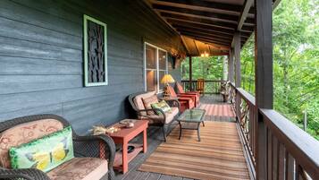 A covered porch with wicker furniture, a table, and a bench.