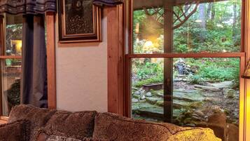 Una habitación con un ventanal que ofrece vistas a un paisaje natural, un banco de madera y un cuadro en la pared.