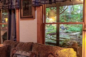 Una habitación con un ventanal que ofrece vistas a un paisaje natural, un banco de madera y un cuadro en la pared.
