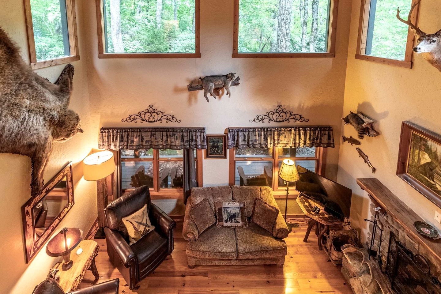 A rustic interior with a fireplace, leather armchairs, and a deer head mounted on the wall.