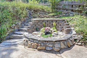 A stone-built structure with a circular stone wall, a small garden area with rocks and plants, and a wooden fence in the background. - Serene Pine-Surrounded Cabin Retreat near Mount Rushmore in South Dakota (Keystone)